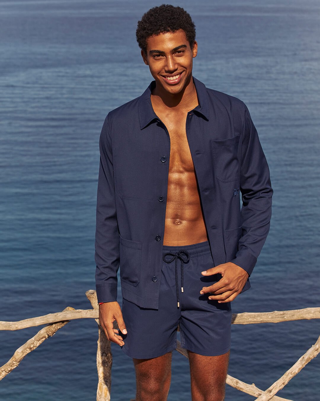 Un uomo al mare che indossa un set coordinato di camicia e pantaloncini.